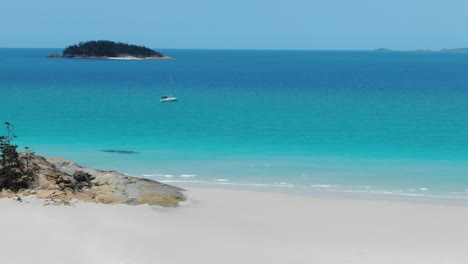 Fliegender-Erstaunlicher-Weißer-Sandstrand,-Der-Sich-Einem-Weißen-Segelboot-Nähert,-Das-Direkt-Vor-Der-Küstenlinie-Festgemacht-Ist,-Drohnenantenne,-Qld-Australien