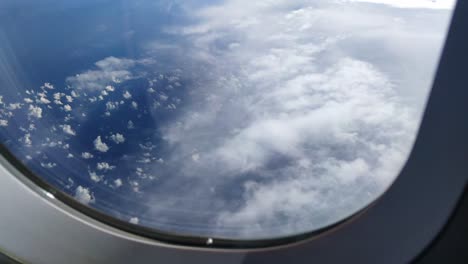 Vista-Desde-El-Avión-Que-Pasa-Sobre-Nubes-Altas,-Sobre-El-Océano-Azul