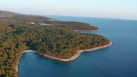 Aerial-reveal-shot-of-Losinj-Island-circling-around-to-show-Mali-Losinj,-Croatia-in-the-distance
