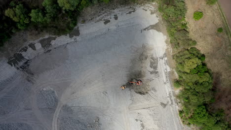 Aerial-drone-footage-of-a-quarry-equipment-extracting-rocks,-sand,-or-gravel-from-the-ground-to-produce-materials