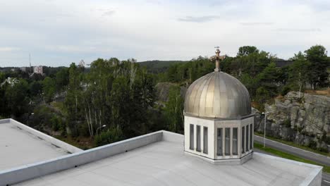 Aerial-view-around-a-bird-on-a-church-cupola-cross,-overcast-day,-in-Sweden---tracking,-drone-shot