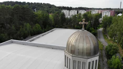 Aerial-flying-around-a-small-metal-bell-tower-with-cross-on-top-in-Sweden