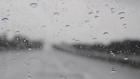 Rain-drops-falling-on-to-a-Car-Windshield-and-wiper-works,-blurred-highway-view-in-dark-environment,-driving-in-the-rain-from-inside-view,-handheld-footage-slow-motion