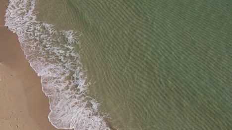 Aerial-pov-with-clear-tropical-ocean-with-small-slow-motion-waves-breaking-on-the-sand