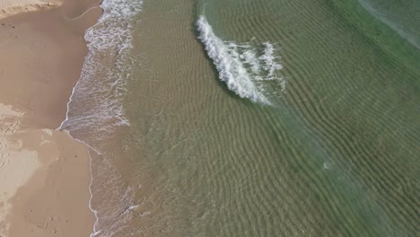 Aerial-drone-static-shot-of-clean-tropical-ocean-waves-crashing-slowly-on-a-virgin-beach-in-Thailand
