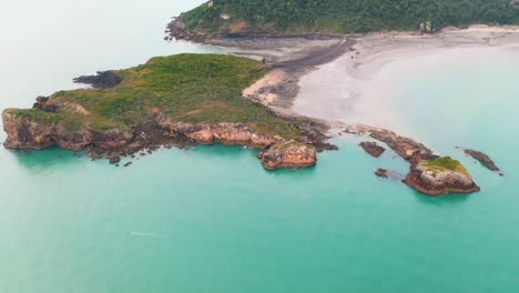 Aerial:-tropical-Australia-coastline,-with-small-boat-sailing-in-turquoise-sea