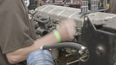 Diesel-mechanic-ratchets-a-bolt-on-the-side-of-a-Diesel-engine-slider-shot-no-face