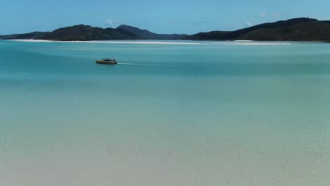 Tourist-boat-navigates-in-turquoise-sea,-Whitehaven-beach-in-Australia