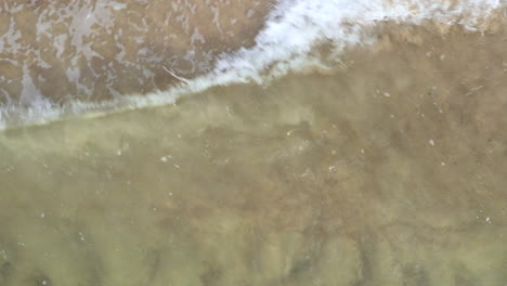 AERIAL:-Close-Up-Top-View-Shot-of-Waves-Crashing-on-the-Shallow-Shore