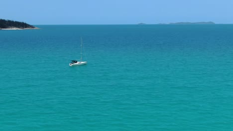 Aerial-view-of-sailing-boat-on-clear-water-near-Whitehaven-beach-in-Australia