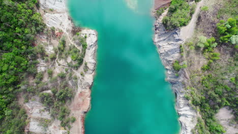 Top-down-fly-over-view-of-a-mine-construction-site-with-blue-big-river