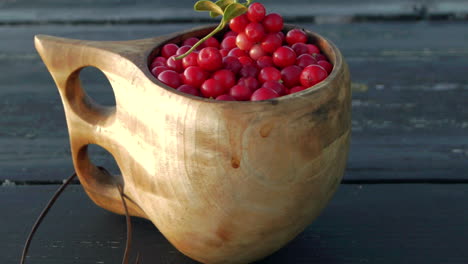 Delicious-Nordic-lingonberries-in-a-handmade-wooden-cup,-panning-dolly-shot