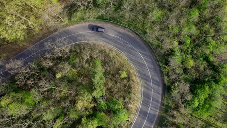 Winding-mountain-road-shot-from-above-with-car-driving-through-the-curve