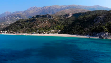 Playa-Paraíso-En-El-Fondo-De-Colinas-Y-Montañas-Bañadas-Por-Agua-De-Mar-Azul-Celeste-En-Albania