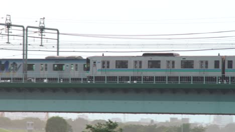 Tren-Jr-Pasando-Por-El-Puente-Marukobashi-Sobre-El-Río-Tamagawa-Al-Atardecer-En-Tokio,-Japón