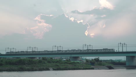 JR-Train-Passing-By-And-Travelling-On-The-Metal-Bridge-Over-The-Tamagawa-River-In-Tokyo,-Japan-On-Sunset-Time