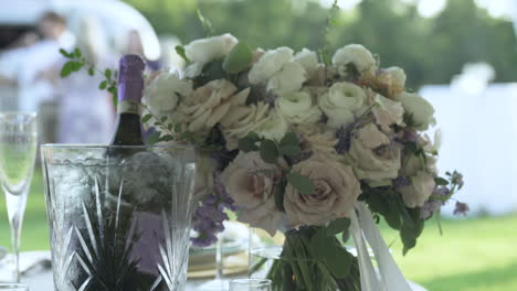 Bouquet-of-flowers-accompanied-by-champagne-bottle-at-wedding-table