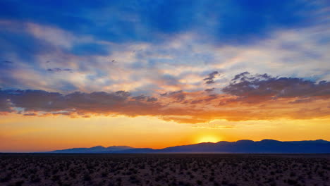 Sunset-hyperlapse-while-moving-quickly-along-the-desert-landscape-as-the-sun-sets-beyond-the-distant-mountain-range