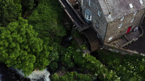 Aerial-shot-of-disused-stone-mill-building-located-in-picturesque-Bushmills,-Northern-Ireland