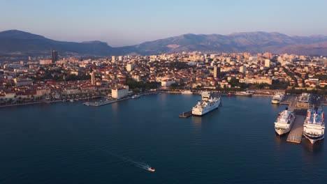 Reveal-drone-during-sunset-of-Split-in-Croatia-with-city-and-sea-infront-and-mountains-in-the-background-in-4k-flying-backwards
