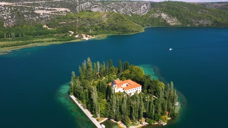 Aerial-reveal-view-flying-backwards-and-spinning-around-Visovac-Monastery-Island-in-Krka-National-Park-with-lakes-and-mountains-in-Dalmatia,-Croatia-filmed-in-4k