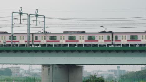 JR-Train-Travels-Across-The-Metro-Rail-Bridge-In-Tamagawa-River-Tokyo,-Japan-During-Misty-Morning