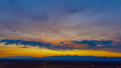 Descending-aerial-hyperlapse-of-a-dramatic-golden-sunset-over-the-Mojave-Desert-landscape-in-summer