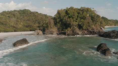 Drone-aerial-zoom-out-of-a-cliff-and-the-shore-of-the-beach-in-National-Park,-Costa-rica