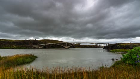 Thick-Gray-Clouds-Over-The-Famous-Hvita-Bridge,-A-Single-Lane-Road-Bridge-Traversing-The-Hvita-River-In-Iceland,-During-An-Overcast-Day---timelapse