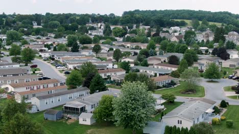 Aerial-push-in-descending-shot-on-mobile-trailer-park,-manufactured-homes,-compact-small-houses-in-neighborhood-community,-American-town-in-rural-suburbia,-USA
