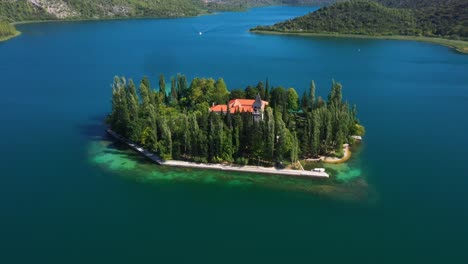 Aerial-view-spinning-around-Visovac-Monastery-Island-in-Krka-National-Park-with-lakes-and-mountains-in-Dalmatia,-Croatia-filmed-in-4k