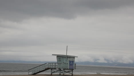 Empty-Lifeguard-Tower-Abandoned,-Waves-Crash-on-Shore,-Foggy-Gloomy-Days,-Slow-Motion