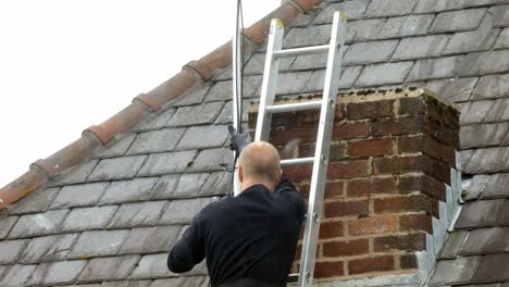 Male-on-ladder-installing-television-aerial-on-home-chimney-roof