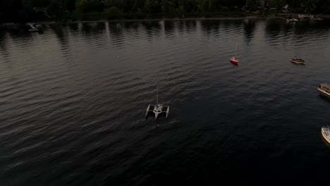 Sailboats-And-Catamaran-Boat-Floating-At-Lake-Memphremagog-Near-The-Beachfront-Houses-In-Quebec,-Canada