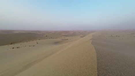 windy-blowing-sand-dune-migrating-at-dusk,-low-angle-timelapse