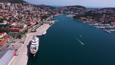 Amazing-reveal-shot-from-left-to-right-in-Dubrovnik,-Croatia-with-mountains,-boats-and-crystal-clear-water-in-4k-panning-down