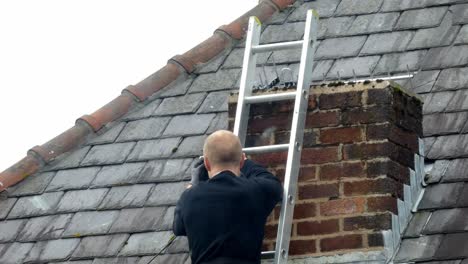 Man-on-ladder-installing-digital-television-aerial-on-home-chimney-roof
