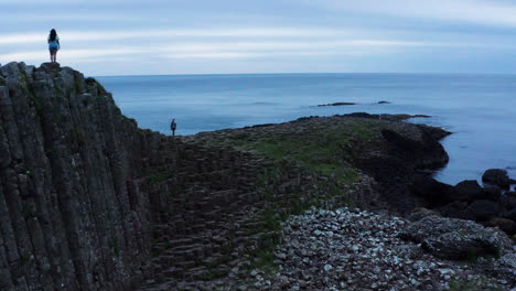 Pan-left-shot-of-tourists-at-the-Giant's-Causeway,-Atlantic-Ocean-in-the-back