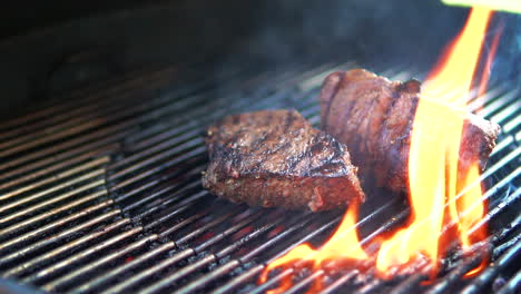 Turning-tender-beef-steaks-being-grilled-on-the-barbecue-flames---slow-motion