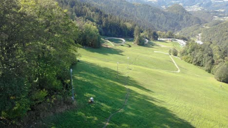 Aerial-View-Of-Open-Grass-Area-Surrounded-By-Trees-In-Lower-Valley-In-Slovenia