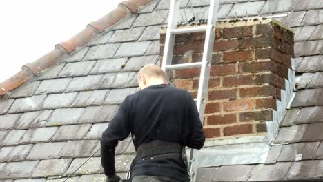 Man-on-ladder-installing-television-aerial-on-home-chimney-roof