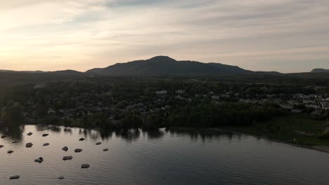 Boats-Moored-Over-The-Calm-Water-Of-Lake-Memphremagog-In-Magog,-Quebec,-Canada-On-A-Sunset---aerial-drone