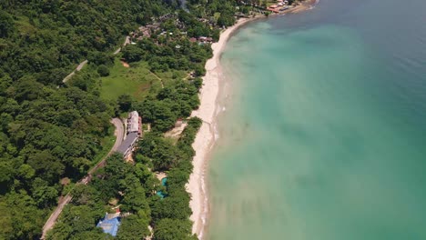drone-dolly-shot-of-a-big-beach-and-jungle-with-road-and-small-resorts-on-the-Island-of-Koh-Chang,-Thailand