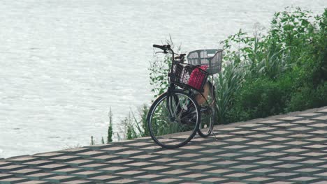 Bicicleta-Japonesa-Con-Canasta-Estacionada-Junto-Al-Río-Tamagawa-Con-Agua-Ondulante-En-El-Fondo-En-Tokio,-Japón