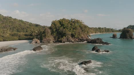 Beautiful-cinematic-drone-aerial-of-a-cliff-and-the-shore-of-the-beach-in-National-Park,-Costa-rica