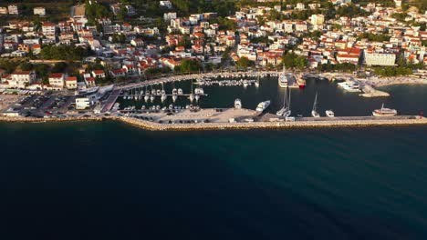 Amazing-aerial-view-flying-forward-into-harbour-during-sunset-in-Baska-Voda,-Croatia-with-mountains,-boats-and-sea-in-4k