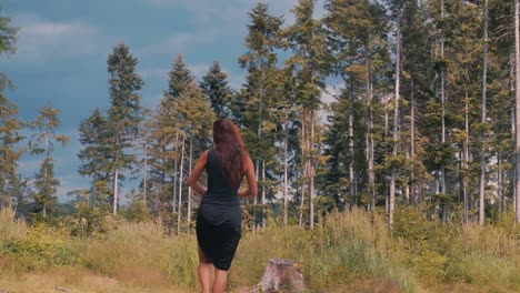 Back-of-Sexy-Woman-in-Black-Dress-Dancing-Barefoot-in-Nature-on-Sunny-Summer-Day-Slow-Motion