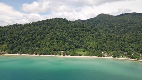 Drone-shot-of-a-long-white-sand-beach-with-tropical-rain-Forrest-jungle-behind-and-mountains
