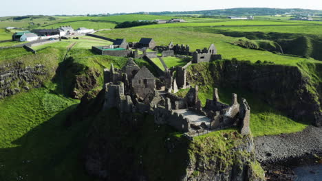 Ireland---Dunluce-Castle-Tourist-Attraction-in-European-Countryside,-Aerial-Drone-Pullaway