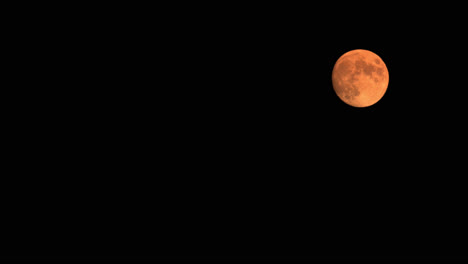 Time-Lapse-Of-Full-Blood-Moon-Rising-In-Sky,-Illuminated-Glowing-Orange